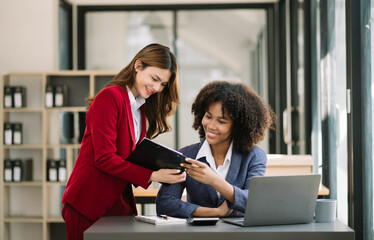 Two businesswoman discuss investment project working and planning strategy with tablet laptop...