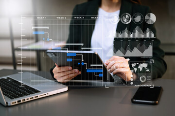 Businessman hand Project manager working and update tasks and Gantt chart scheduling virtual diagram.with smart phone, tablet and laptop in office.