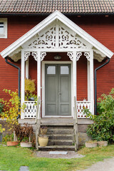 Scandinavian red wooden entrance with white decorated facade