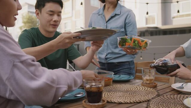 Mom enjoy cooking for family day dining at dine table cozy patio front yard home. Mum passing food serving drink to group four asia people young adult man woman friend fun joy relax warm picnic eating