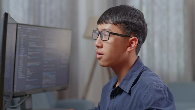 Close Up Of Asian Boy Programmer Smiling And Crossing Her Arms While Creating Software Engineer Developing App, Program, Video Game On Desktop Computer At Home
