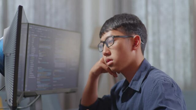 Close Up Of Asian Boy Programmer Being Bored Creating Software Engineer Developing App, Program, Video Game On Desktop Computer At Home. Terminal With Coding Language 
