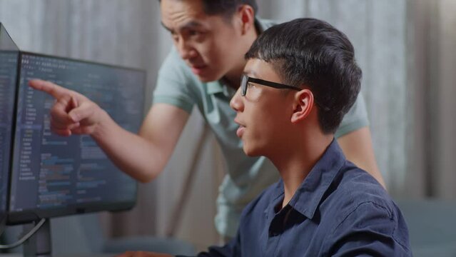 Close Up Of Asian Boy Students Studying Software Code From Male Teacher Or Father
