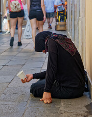 A homeless female beggar is begging on the street in Venice, Italy