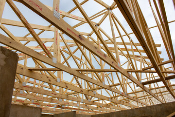 Diagonal view of wooden frame of a lattice of roof beams on a building under construction 