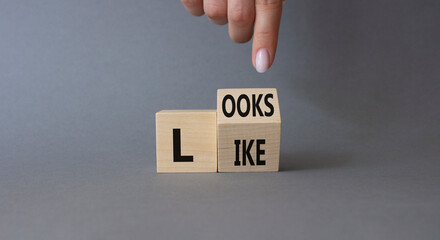 Looks like symbol. Businessman hand points at turned wooden cubes with words Looks like. Beautiful grey background. Business and Looks like concept. Copy space