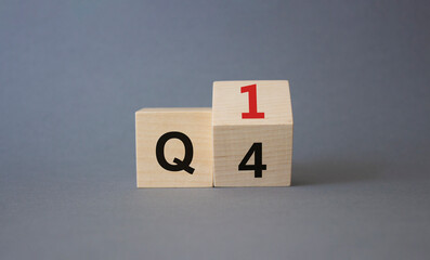 From 4th Quarter to 1st symbol. Turned wooden cube with words 4th Quarter and 1st Quarter. Beautiful grey background. Business and Quarter concept. Copy space