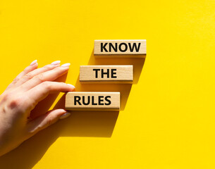 Know the rules symbol. Wooden blocks with words Know the rules. Beautiful yellow background. Businessman hand. Business and Know the rules concept. Copy space. - obrazy, fototapety, plakaty