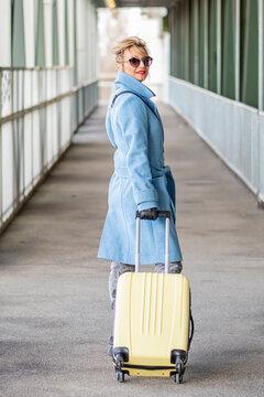 A blonde woman 40-45 years old with a suitcase.