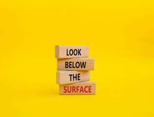 Look below the surface symbol. Concept word Look below the surface on wooden blocks. Beautiful yellow background. Business and Look below the surface concept. Copy space