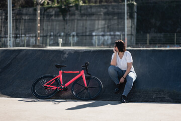 Obraz premium woman resting next to a bicycle in the skate park