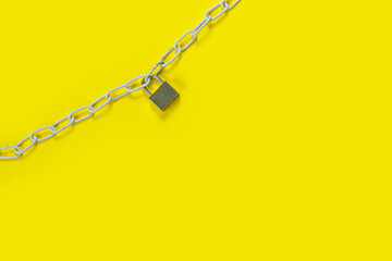 The padlock and chains on yellow background. Flat lay, top view with copy space for text.