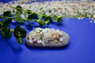 herbal salt on a stone with a green leaf on a blue background with herbal salt lying around, copy space