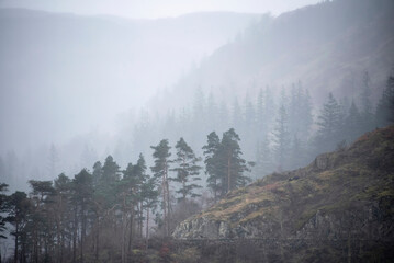 Beautiful calm peaceful Winter landscape over Thirlmere in Lake District with mist and layers visible in the distance