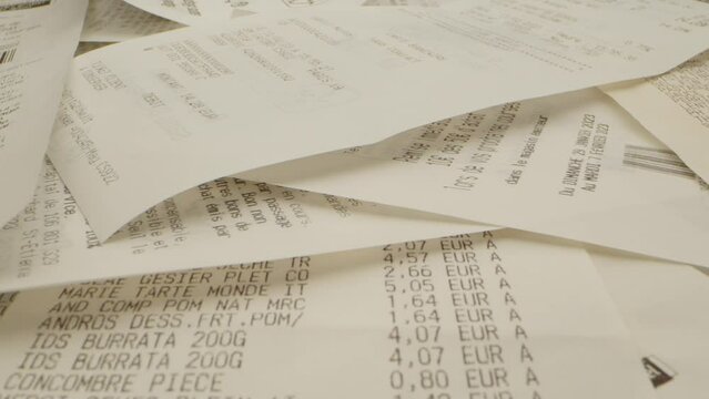 gros plan de plusieurs tickets de caisses &eacute;parpill&eacute;s avec  deux pi&egrave;ces de monnaie en euros