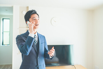 スマートフォンで電話をする不動産営業マンの若い男性