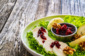 Fresh salad - goat cheese, pear, jam, lettuce and walnuts on wooden background

