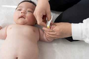 母親のが赤ちゃんの手の爪を切るイメージ（0歳2か月、男の子、日本人）