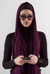 Woman in black stylish fashionable clothes Muslim headscarf. Lady using smart phone, close up...