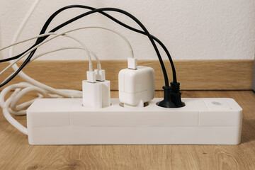 Modern cable connector for overloaded power boards at home. The extension cord is filled with...