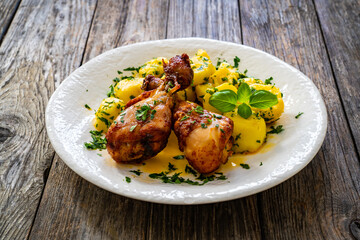 BBQ chicken drumsticks with fried potatoes, lettuce and ketchup on wooden table
