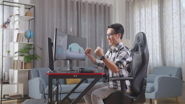 Side View Of Asian Male Automotive Designer Screams Goal For Success Celebration While Working On 3D Model Of Ev Car On The Desktop Computers At Home
