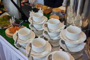 Stacked empty teacups with teaspoons at a function over.