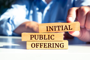 Close up on businessman holding a wooden block with "Initial Public Offering" message