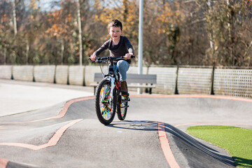 A young child rides the new Park BMX pump track on his bike on a summer evening