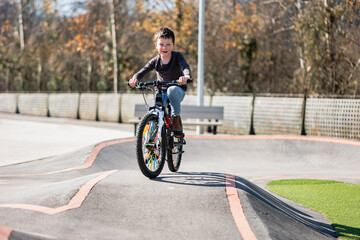 Fototapeta premium A young child rides the new Park BMX pump track on his bike on a summer evening