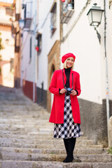 Stylish travelling lady standing on stairs in town and smiling