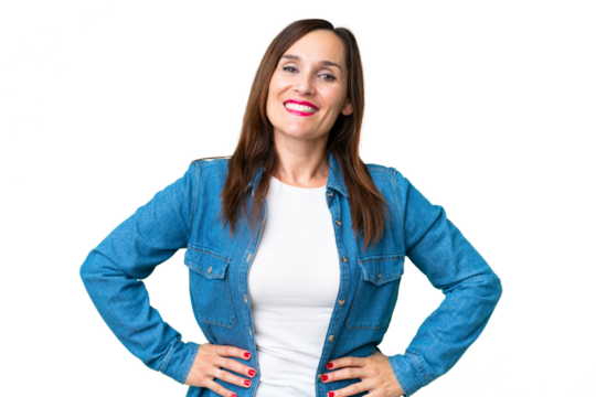 Middle age woman over isolated chroma key background posing with arms at hip and smiling