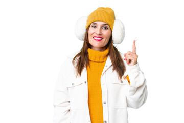 Middle age woman wearing winter muffs over isolated chroma key background pointing with the index finger a great idea