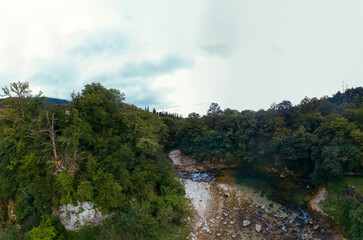 The Abhesi waterfall among green trees, a mountain river with clear water. the stones are turned by the stream. Tourist place for rest and swimming. Aerial view. western Georgia