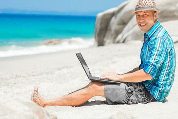 A Happy man guy with laptop near the seashore weekend travel