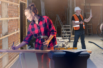 Woman works at construction site. Girl carpenter at construction site. Furniture maker makes marks on blackboard. Male builder in unfinished building. Construction company employees