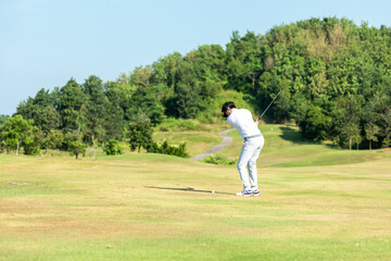 Golfer sport course golf ball fairway.  People lifestyle man playing game and swing golf tee off on the green grass.  Asian man player game shot in summer.  Healthy and Sport outdoor