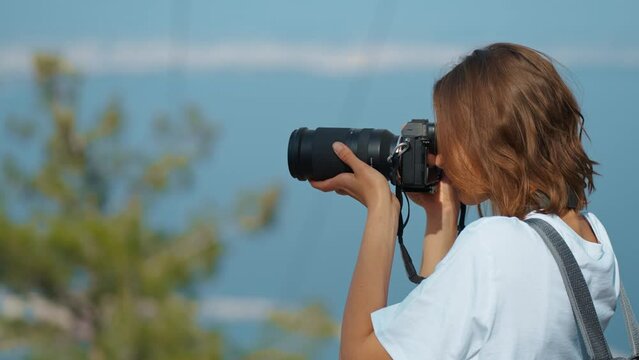 pretty woman travel blogger taking photo or video on professional camera, viewpoint among mountains and blue sky, cableway on background. viewpoint of Tunektepe Teleferik, Antalya, Turkey