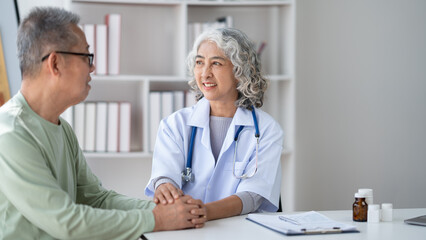 Obraz premium Expert Asian senior female doctor talking with her male patient show support and care.