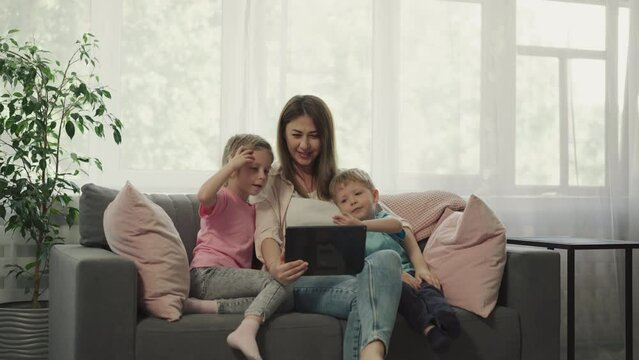 Mother and children talk to father on video call via tablet