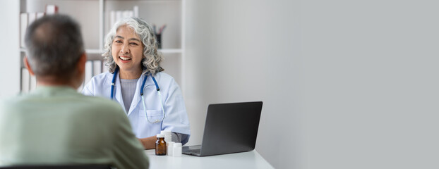 Serious middle-aged female doctor pediatrician talk with male patient, examine and discussing about the illness.