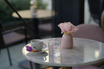 A cup of coffee and the flower on the table in the cafe in spring. Cute table in the morning coffee house. Pretty rest space in the restaurant  
