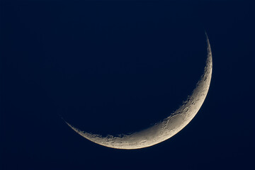 A thin crescent moon on a dark blue background