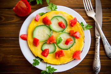 Fried omelet with zucchini, tomatoes, herbs in a plate