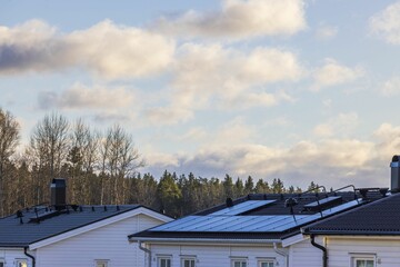 Gorgeous view of villa roof equipped with solar panel against background of blue sky with white clouds. Sweden.