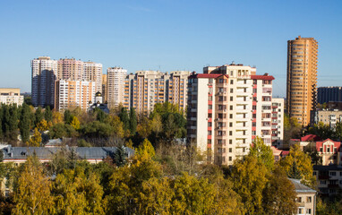 Fototapeta premium Urban beautiful landscape - panoramic view of residential multi-storey modern houses among autumn trees on a sunny October day in Reutov Moscow region and copy space