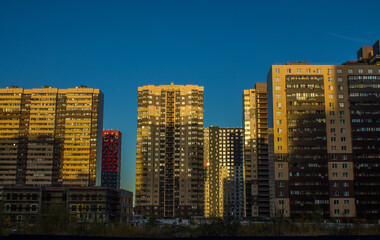 Tall modern residential buildings of yellow-blue color in the city of Reutov near Moscow against the background of a bright clear sky on a sunny day