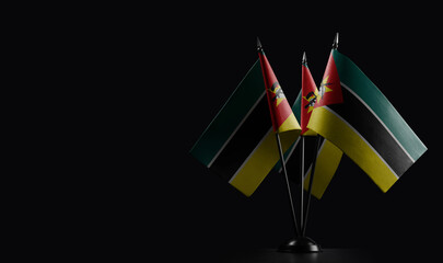 Small national flags of the Mozambique on a black background