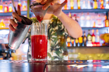 bartender making red cocktail in a nightclub bar
