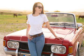 beautiful girl in retro style posing near vintage red cabriolet car.